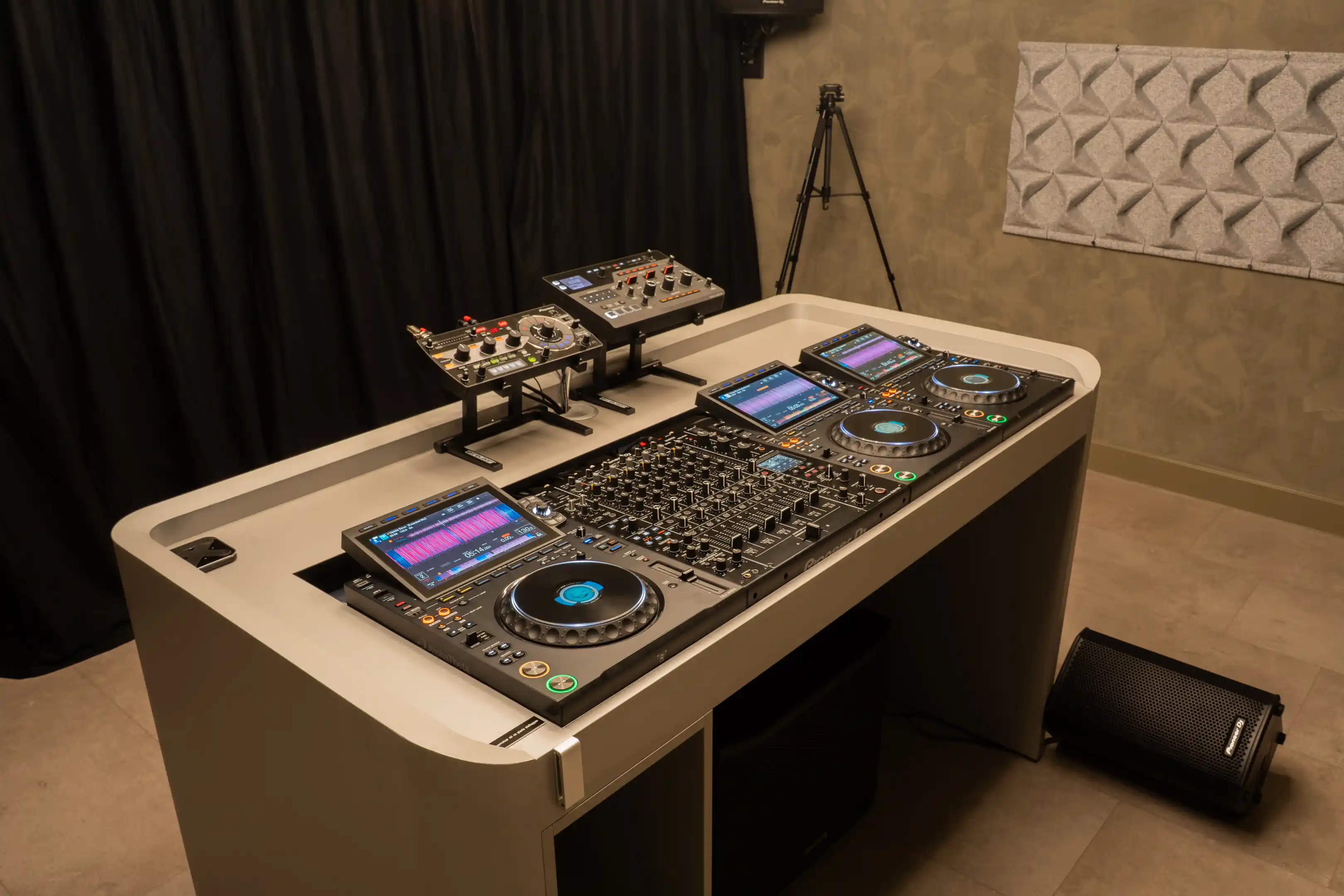 De DJ-booth met drie CDJ-3000X-spelers, de DJM-V10 en twee effect units op een standaard